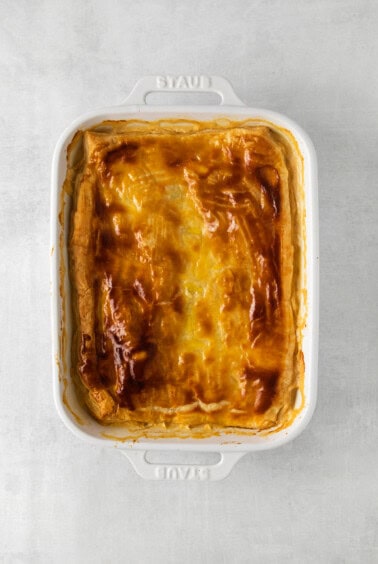 a white casserole dish with a cheesy dish in it.