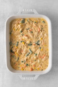 a white casserole dish filled with chicken and vegetables.