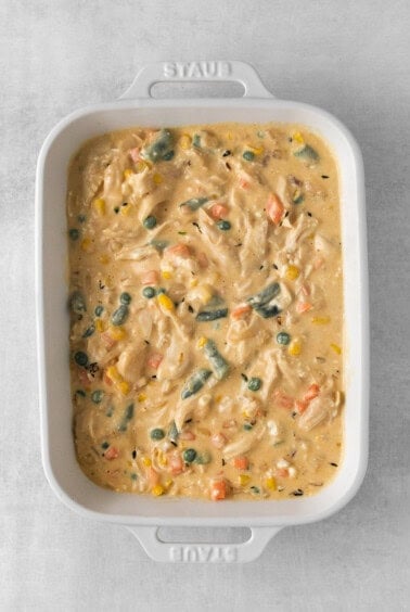 a white casserole dish filled with chicken and vegetables.