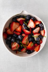 a white bowl with berries and blueberries in it.