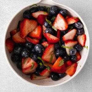 a white bowl with berries and blueberries in it.