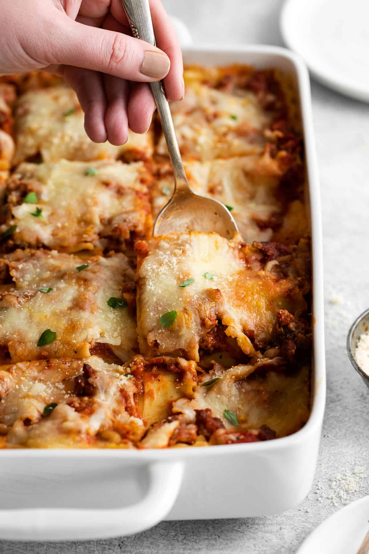 A spoon scooping a piece of lasagna. 