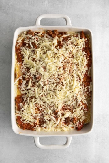 Assembled lasagna topped with cheese.