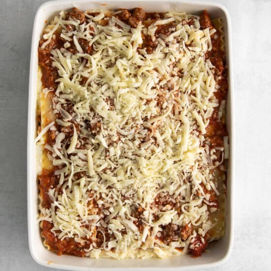 Assembled lasagna topped with cheese.