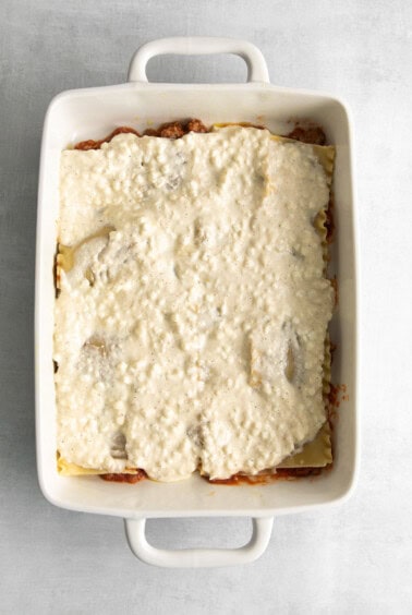 Layering lasagna noodles, sauce, and cottage cheese in a casserole dish.