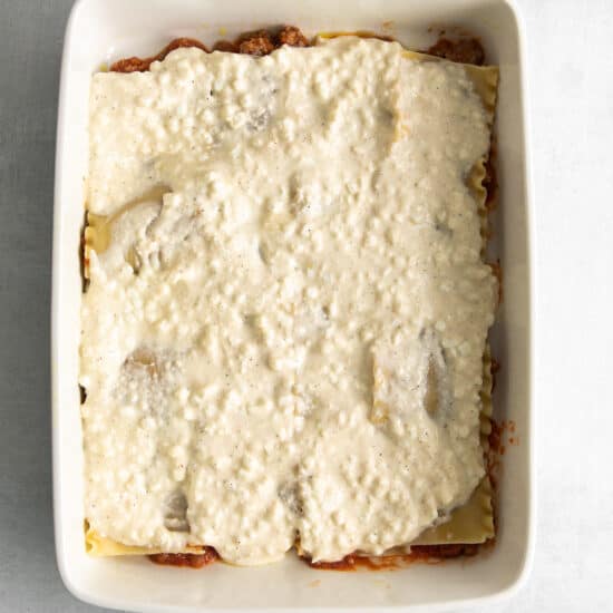 Layering lasagna noodles, sauce, and cottage cheese in a casserole dish.