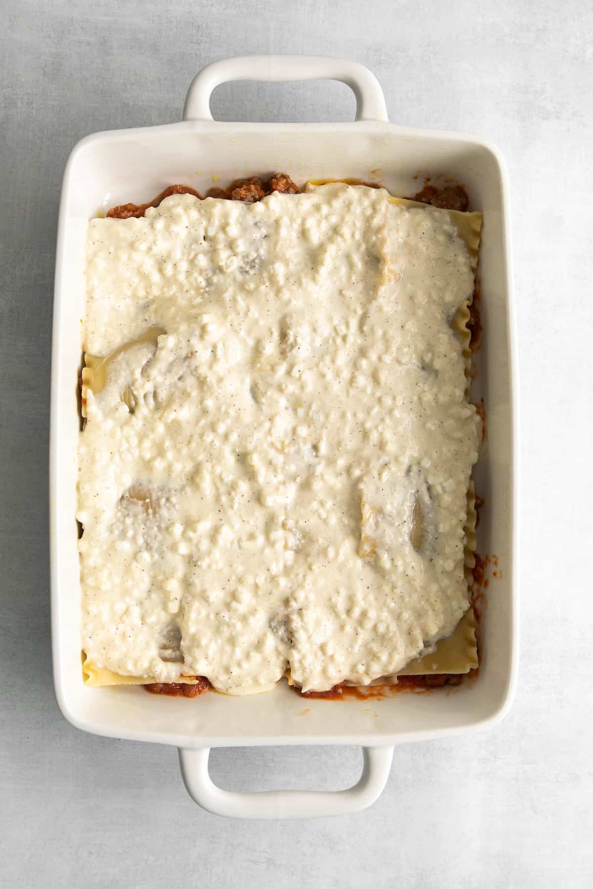 Layering lasagna noodles, sauce, and cottage cheese in a casserole dish.