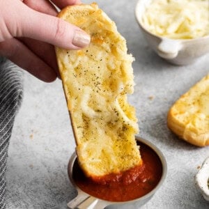 a person dipping a piece of bread into sauce.