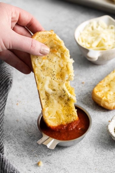 a person dipping a piece of bread into sauce.