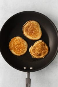 three pancakes are being cooked in a frying pan.