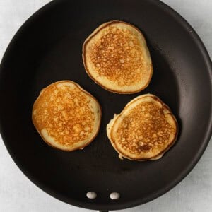 three pancakes are being cooked in a frying pan.