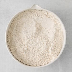 flour in a white bowl on a white surface.