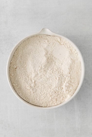 flour in a white bowl on a white surface.