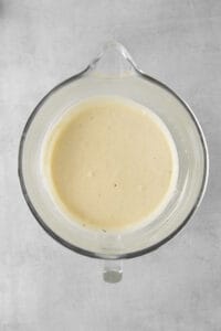a bowl of white sauce on a gray surface.