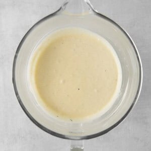 a bowl of white sauce on a gray surface.