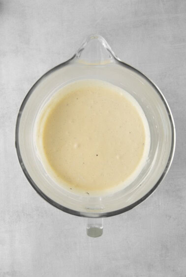 a bowl of white sauce on a gray surface.