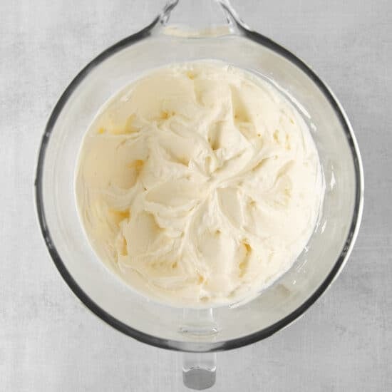 whipped cream in a glass bowl on a gray background.