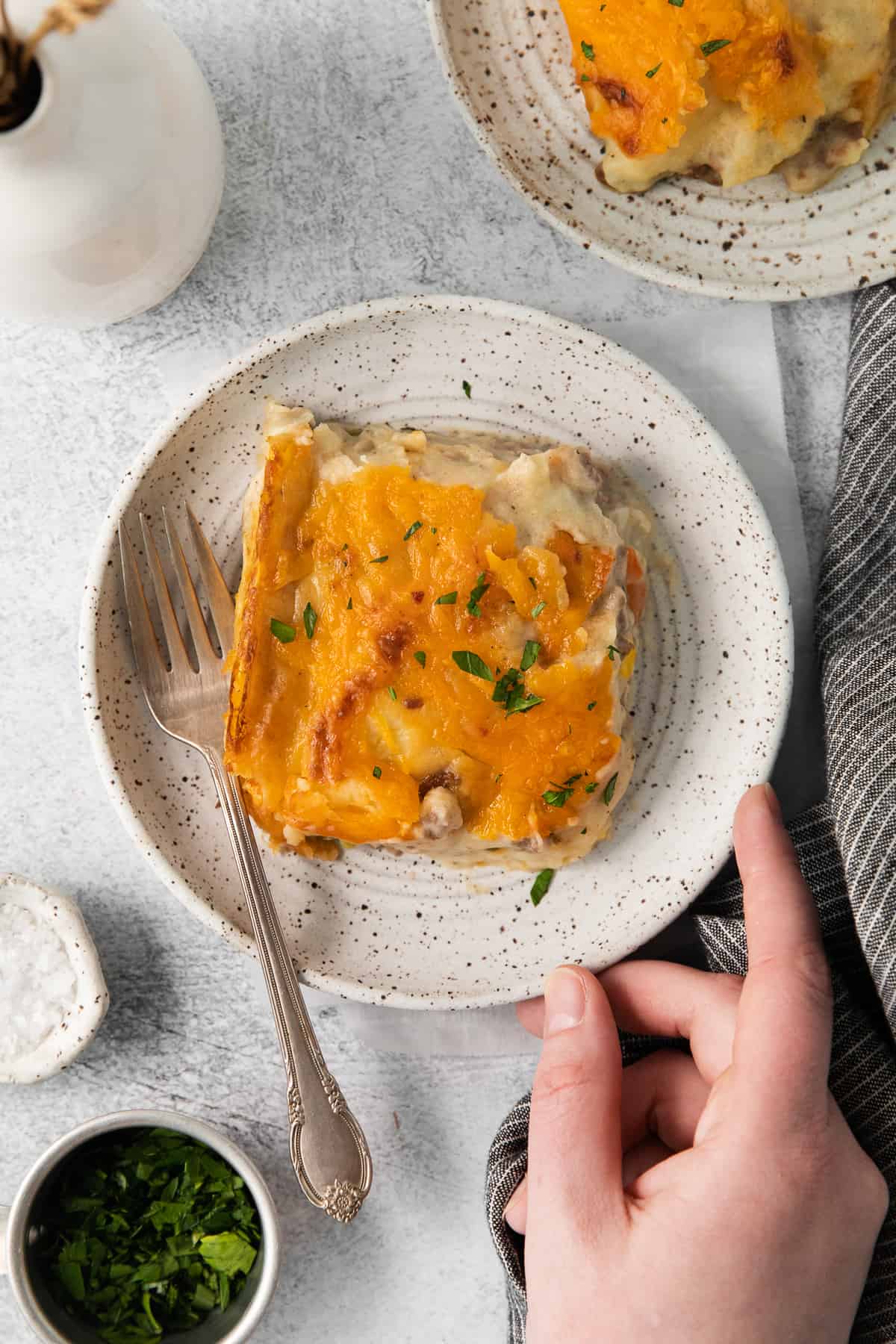 Slice of cheesy shepherd's pie on a plate with a fork.