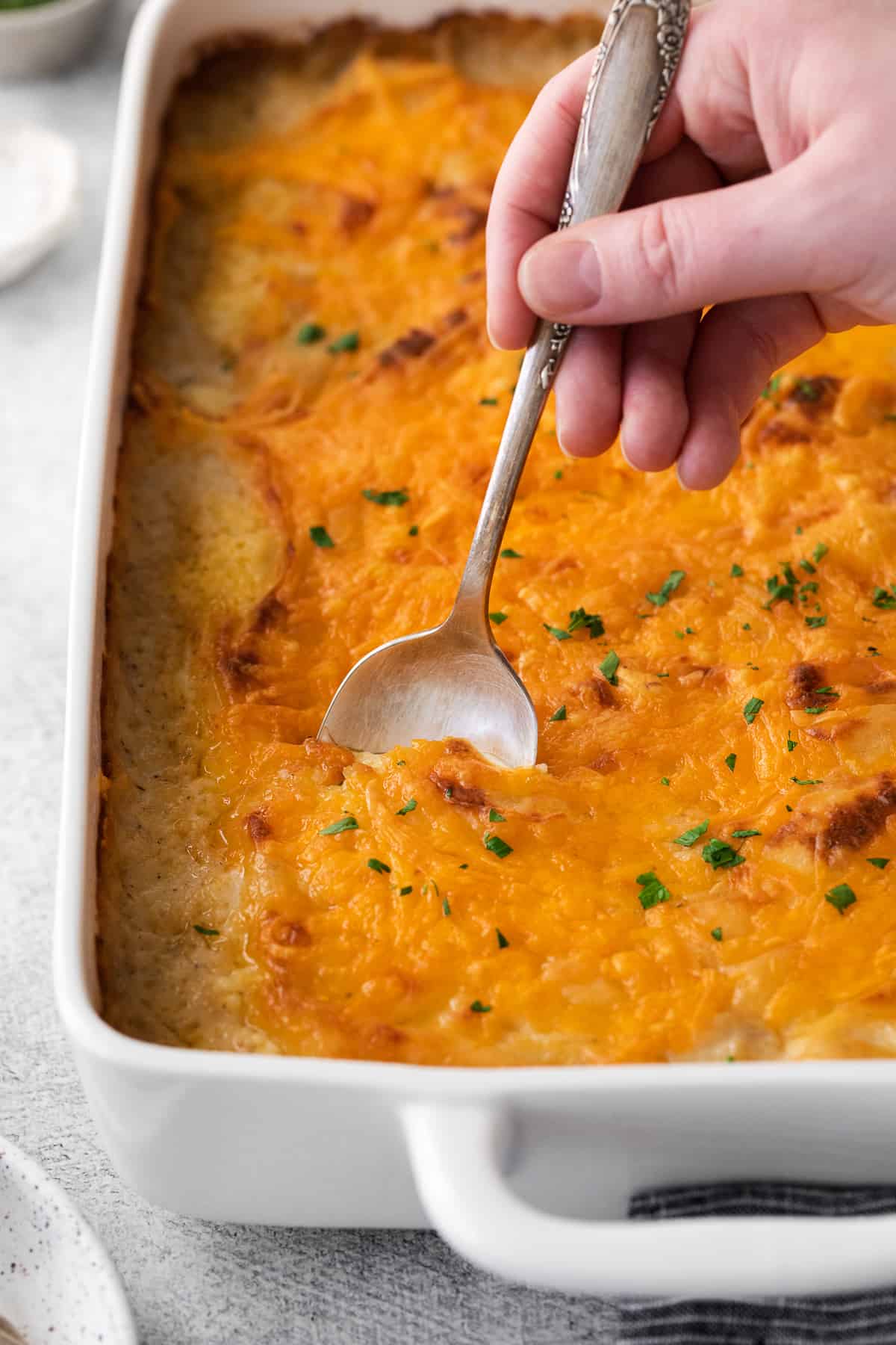Cheesy shepherd's pie in a casserole dish being scooped with a spoon.