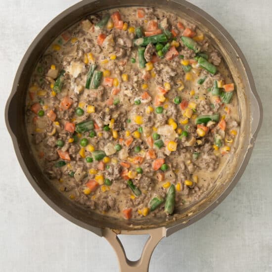 a skillet filled with vegetables and meat.