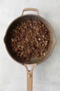 a frying pan filled with ground beef and onions.