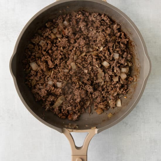 a frying pan filled with ground beef and onions.