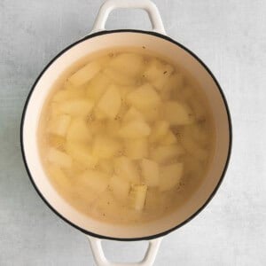 a pot of soup with potatoes in it on a gray background.