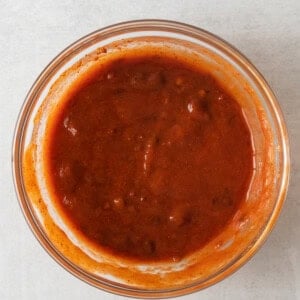 a bowl of sauce on a white surface.