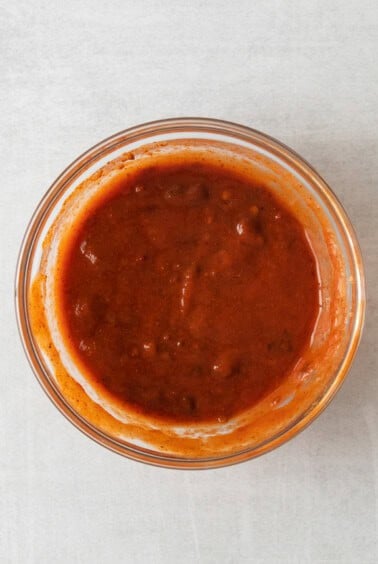 a bowl of sauce on a white surface.
