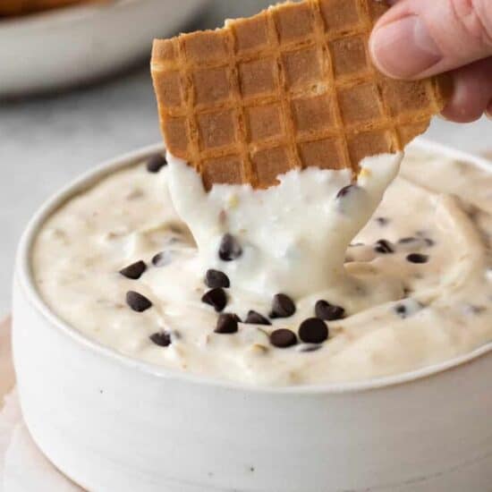 Waffle cone being dipped into cannoli dip.