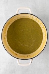 a pot of green soup on a white surface.