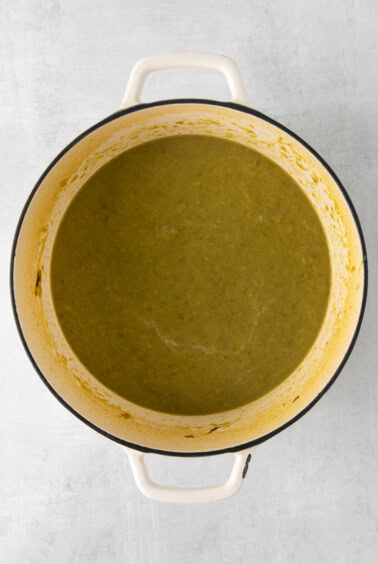a pot of green soup on a white surface.