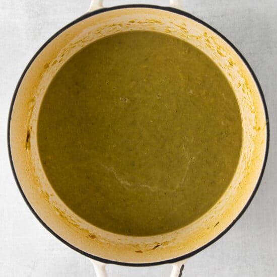 a pot of green soup on a white surface.