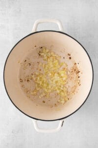 a pot filled with onions and garlic on a white background.