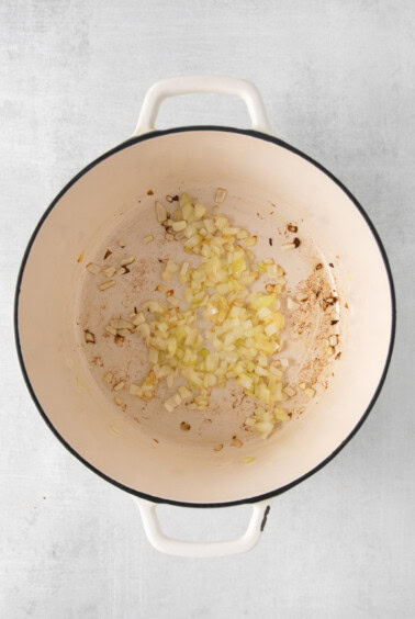 a pot filled with onions and garlic on a white background.