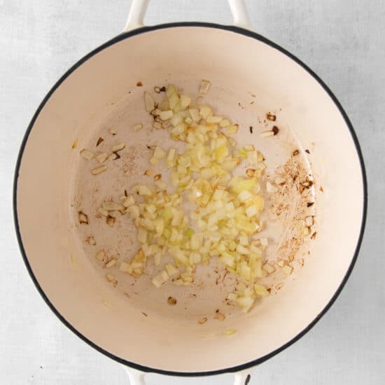 a pot filled with onions and garlic on a white background.