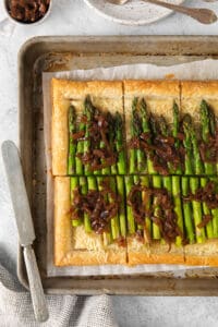 a tart with asparagus and onions on a baking sheet.