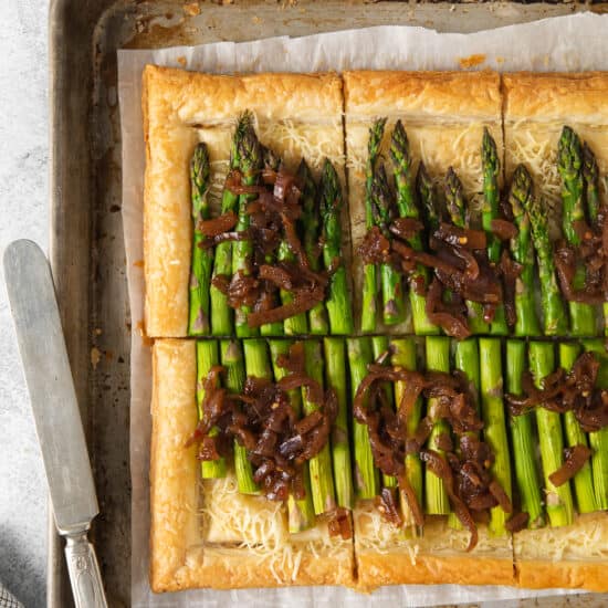 a tart with asparagus and onions on a baking sheet.