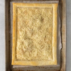 a square pastry with cheese on a baking sheet.