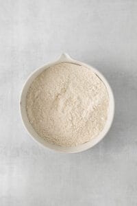 a white bowl filled with flour on a gray surface.