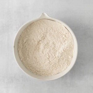 a white bowl filled with flour on a gray surface.