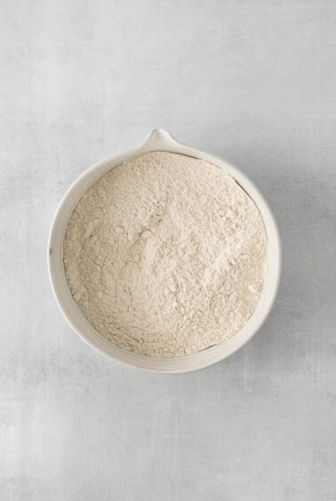 a white bowl filled with flour on a gray surface.