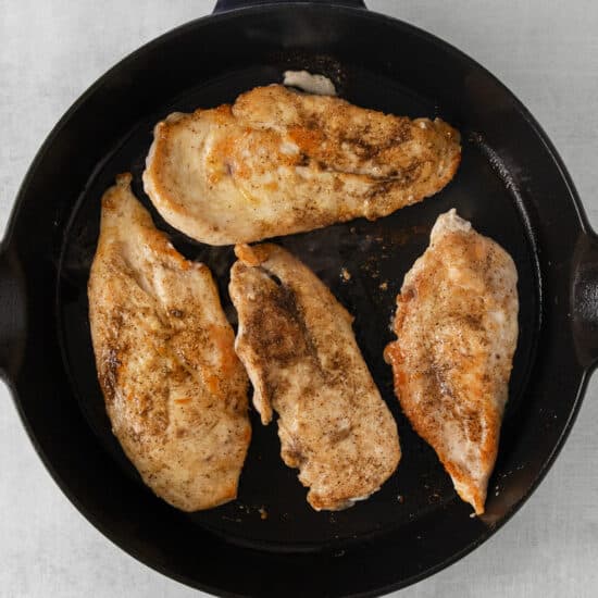 chicken breasts in a skillet on a white background.