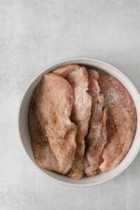 chicken breasts in a white bowl on a gray background.