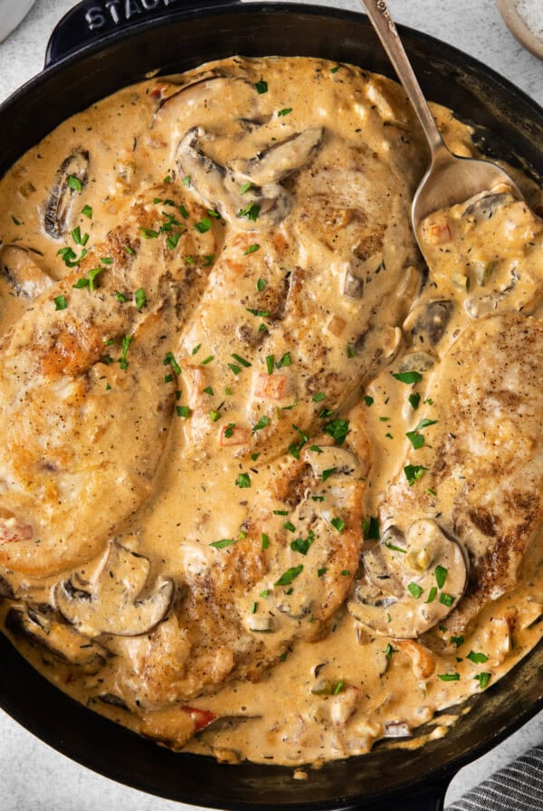 a skillet filled with chicken and mushrooms in a creamy sauce.