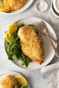 stuffed chicken breasts on a white plate with lemon wedges.