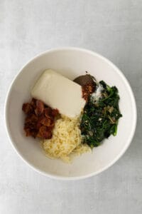 a bowl filled with spinach, cheese and bacon.