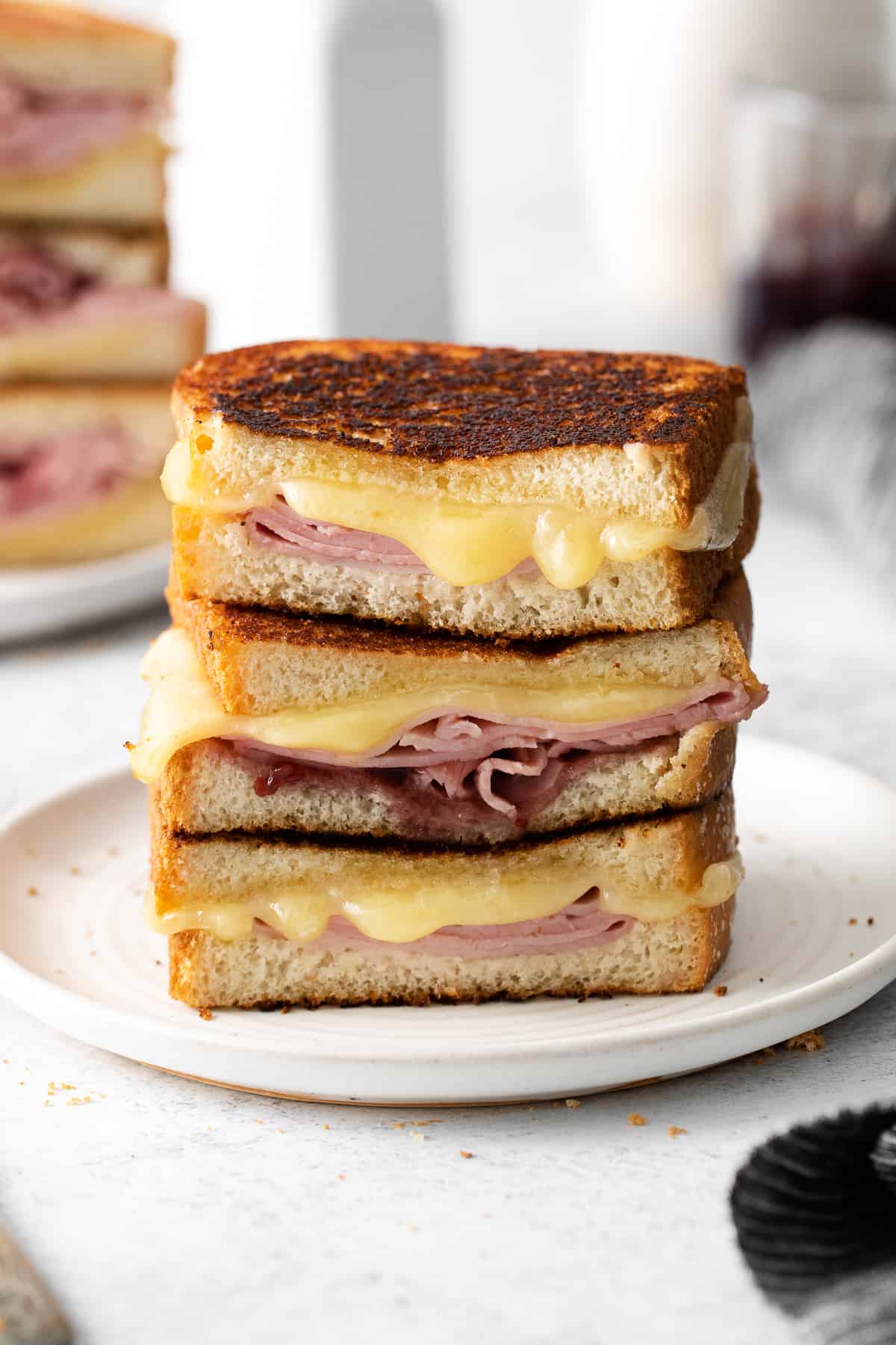 Grilled ham and cheese sandwich stacked on a plate.