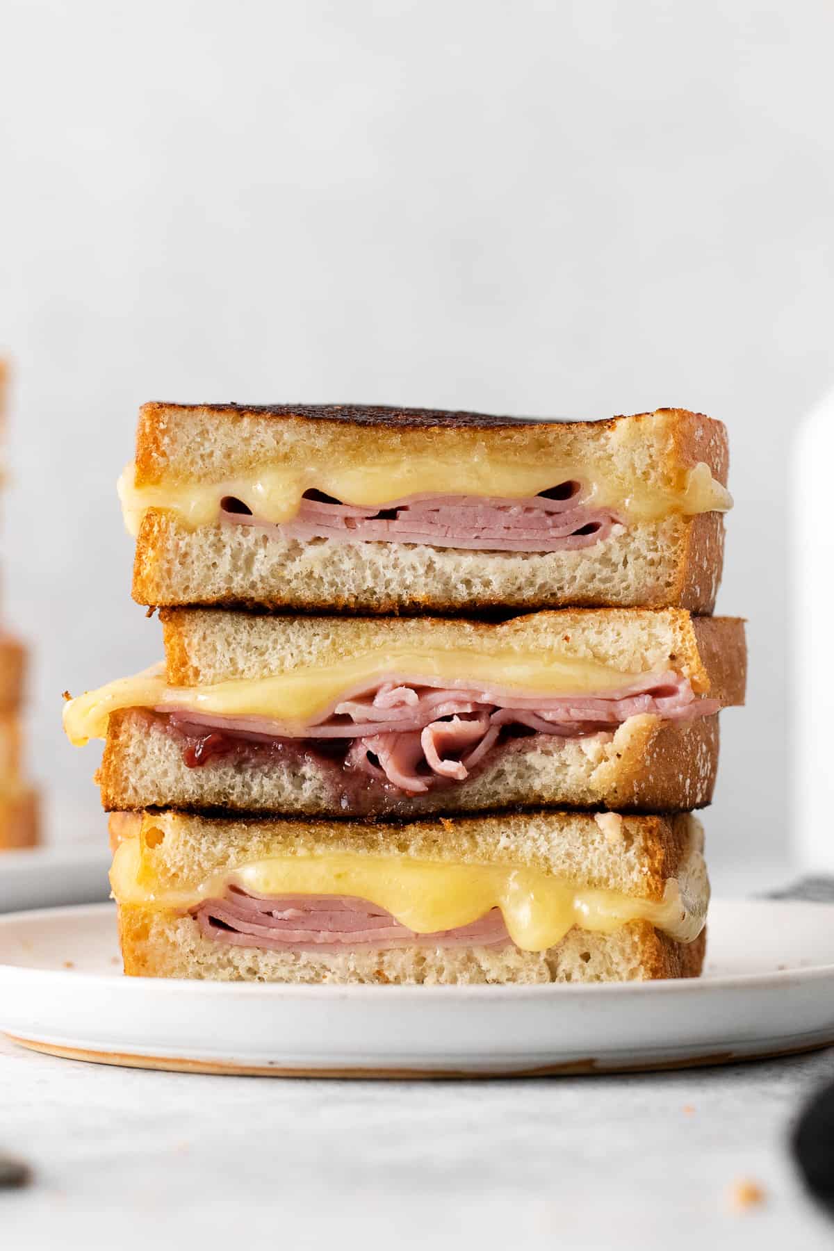 Grilled ham and cheese sandwiches stacked on a plate.