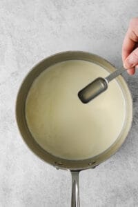 a person pouring milk into a pan.